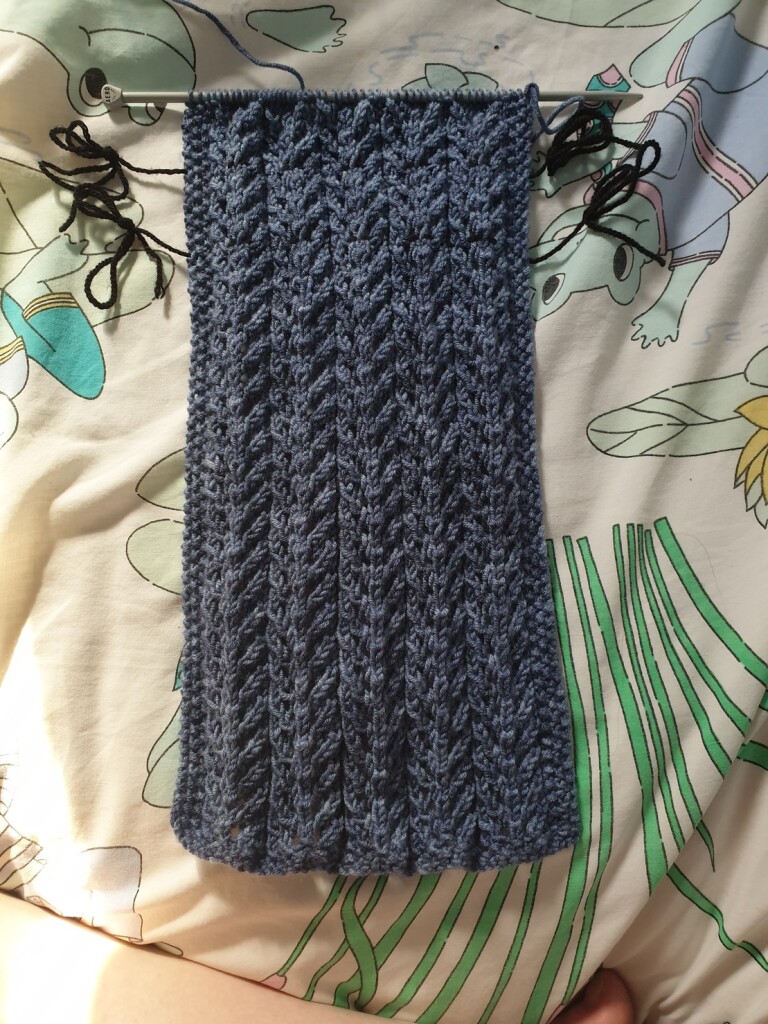blue-grey scarf with tree bark patterning, still attached to knitting needles bc not finished lol