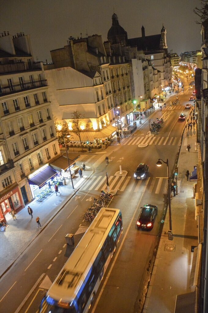 An overhead view of a street in Paris that has a two-way protected bike lane on one side and two lanes of car traffic on the other.