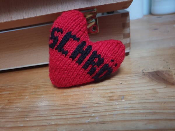knitted red heart with schrödinger embroidered around it