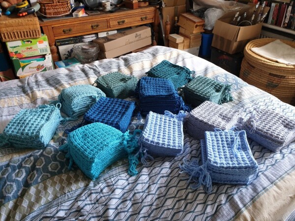 over ten piles of blanket squares in seven different colours on a double bed