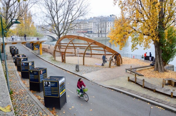 A cyclist uses a car-free street on the banks of the River Seine in Paris. It is lined with a park and trees.