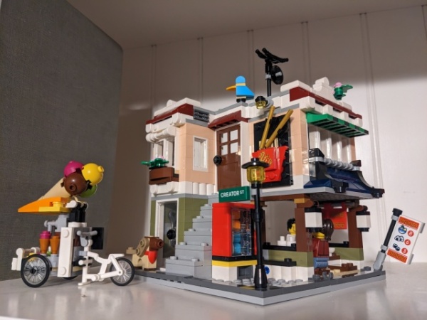 LEGO set #31131, depicting a small street corner with a noodle shop and apartment, assembled and on display on a shelf